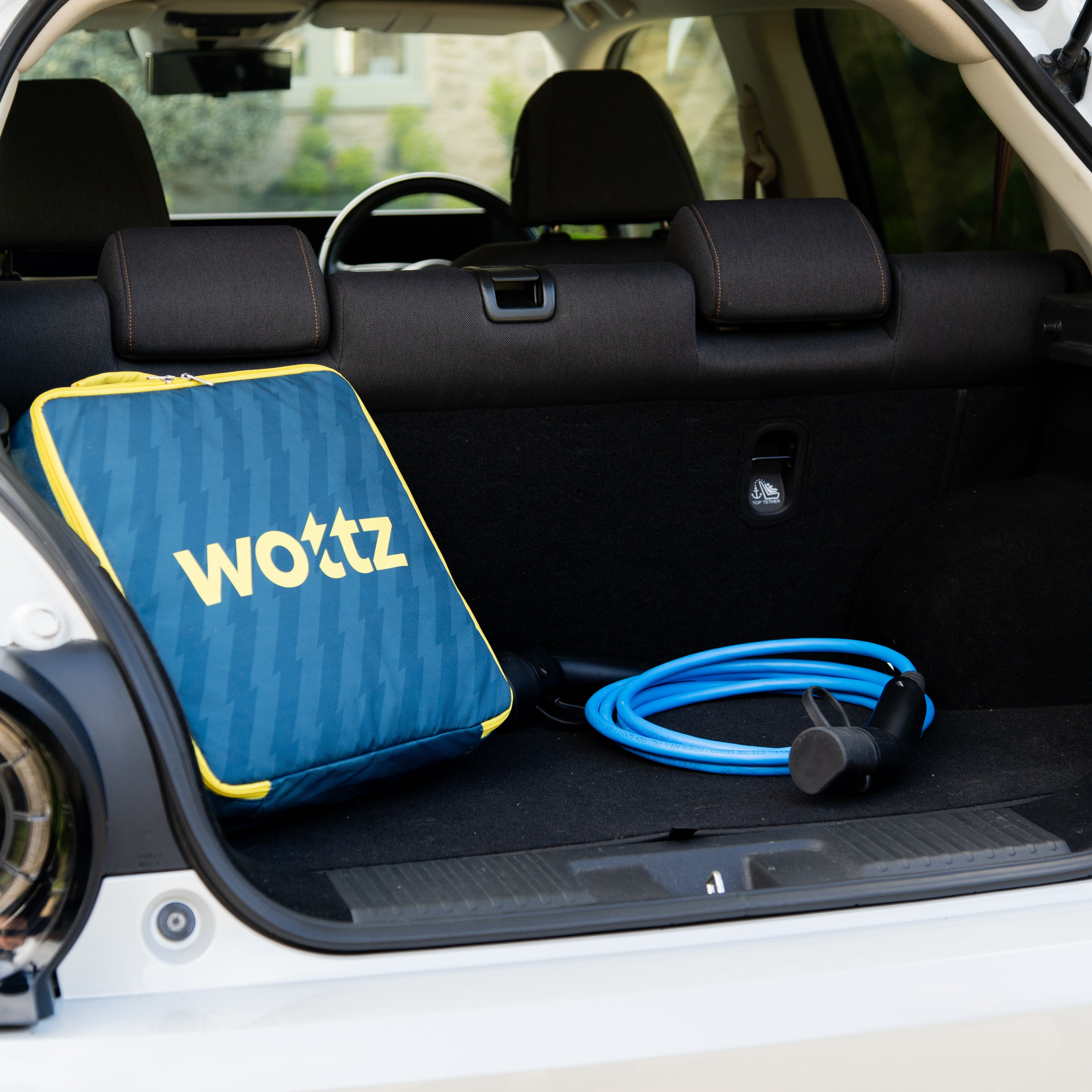 Wottz product in a car trunk with a blue and yellow bag and cable.