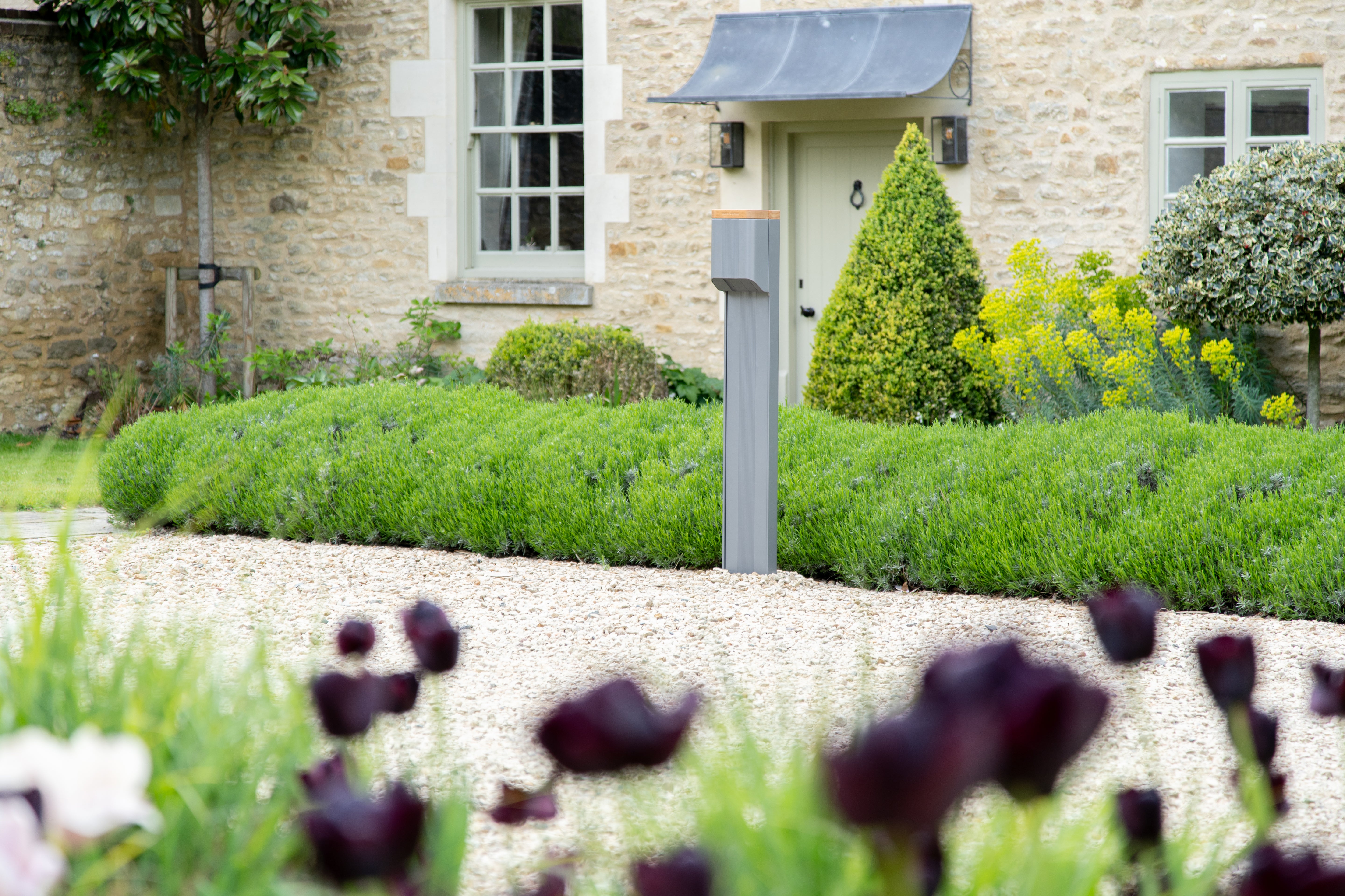 Freestanding Simpson & Partners EV charge post outside a Cotswolds stone cottage with lavender hedging