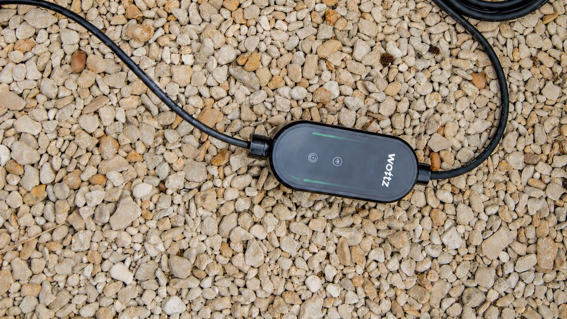 Wottz portable EV charger control box with cables on gravel showing green LED status indicator